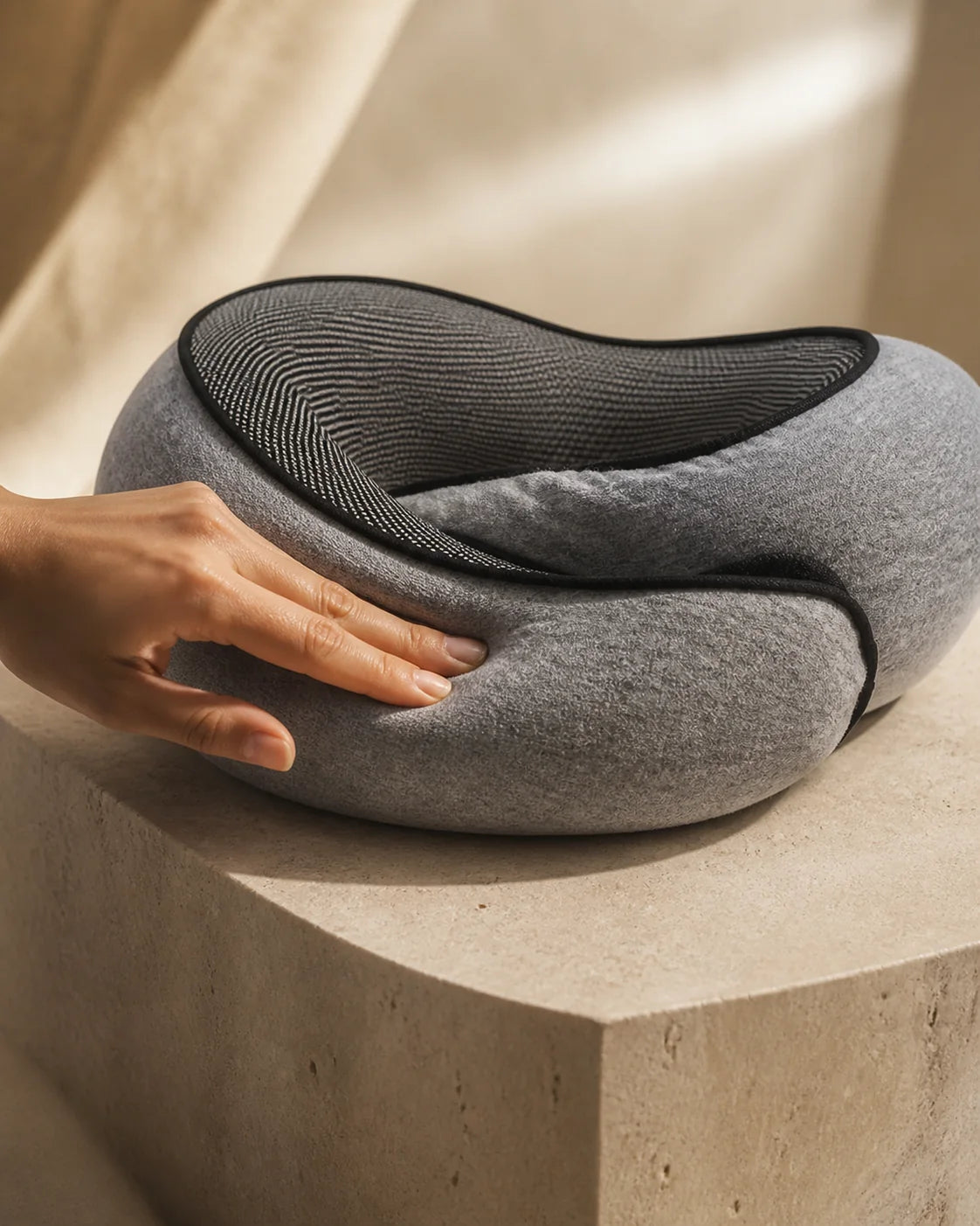 A hand gently pressing the grey CloudNeck memory foam pillow